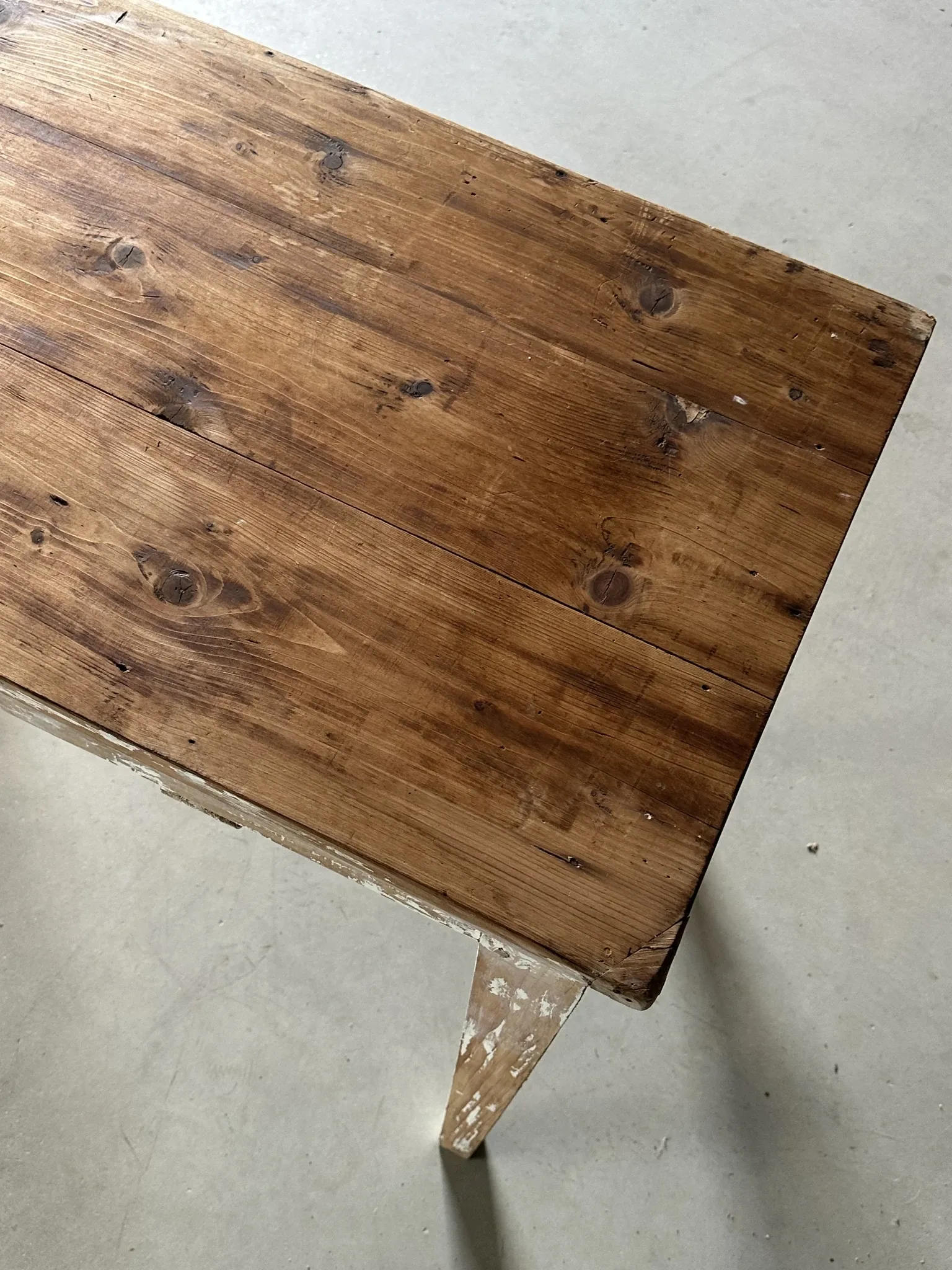 Vintage table made of raw wood with a distressed white base.