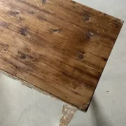 Vintage table made of raw wood with a distressed white base.