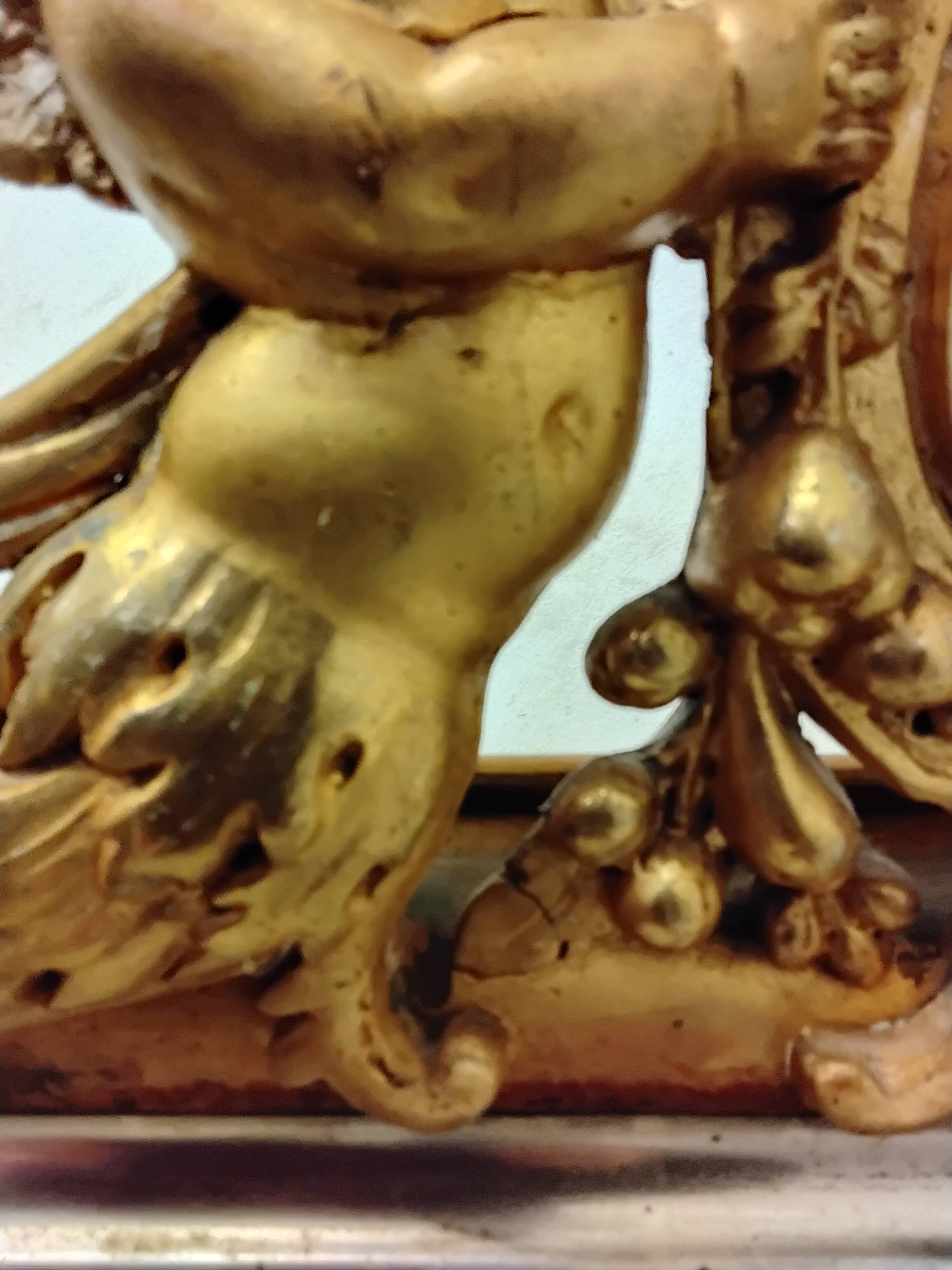 Antique mirror with a gilded frame and cherubs.