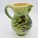 Green stoneware pitcher with flower and brown bird decoration