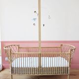 Newly refurbished rattan baby crib, with an oak arrow for a mobile.