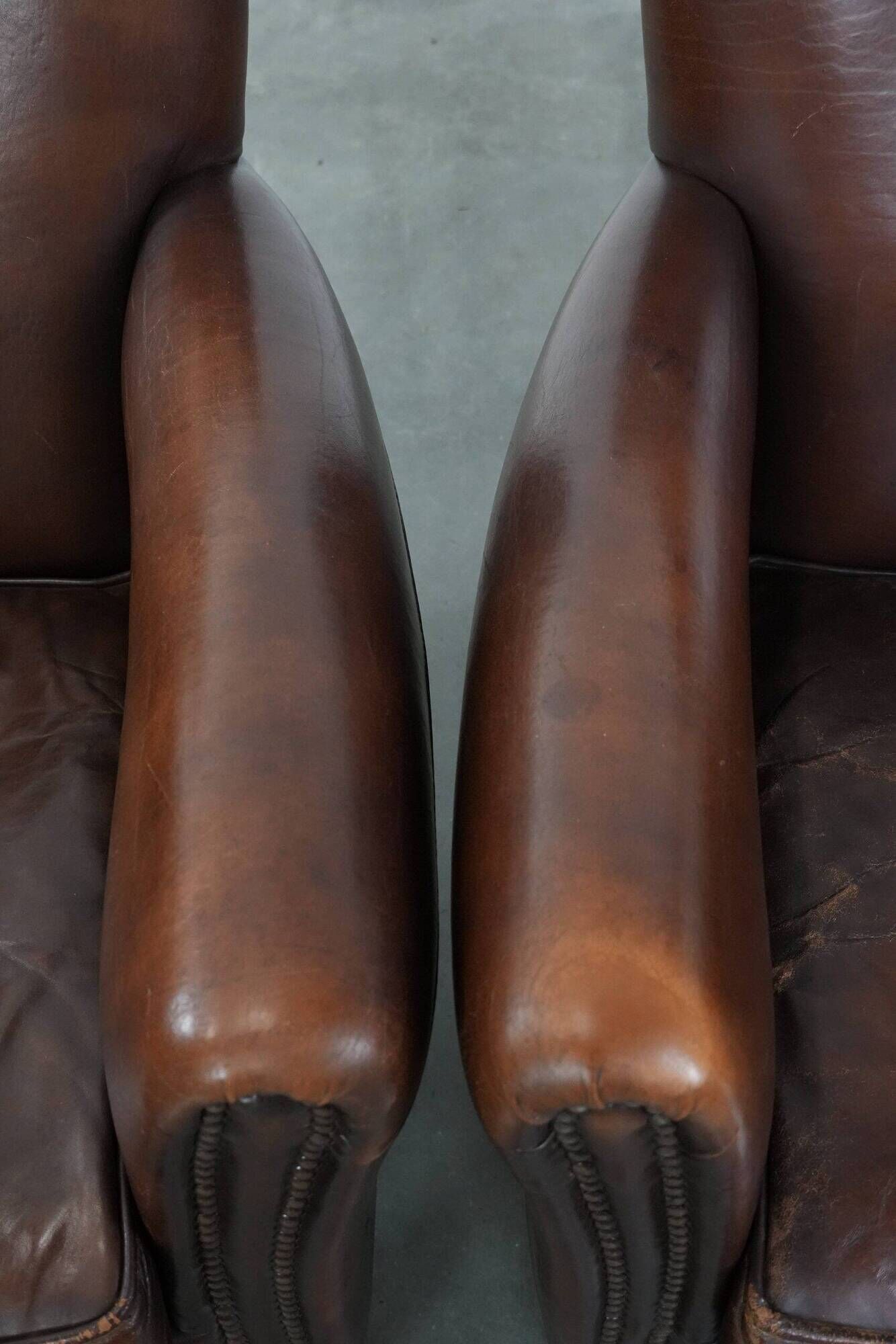 Ensemble de deux fauteuils en cuir de mouton vintage au caractère marqué.