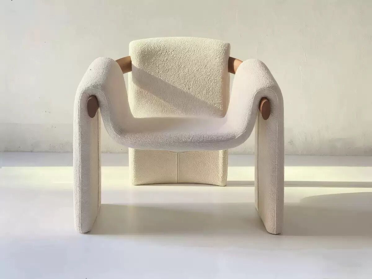 Sculptural lounge armchair in ecru boucle fabric with solid wood details.