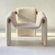 Sculptural lounge armchair in ecru boucle fabric with solid wood details.