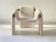 Sculptural lounge armchair in ecru boucle fabric with solid wood details.