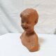 Terracotta bust of a smiling little boy.