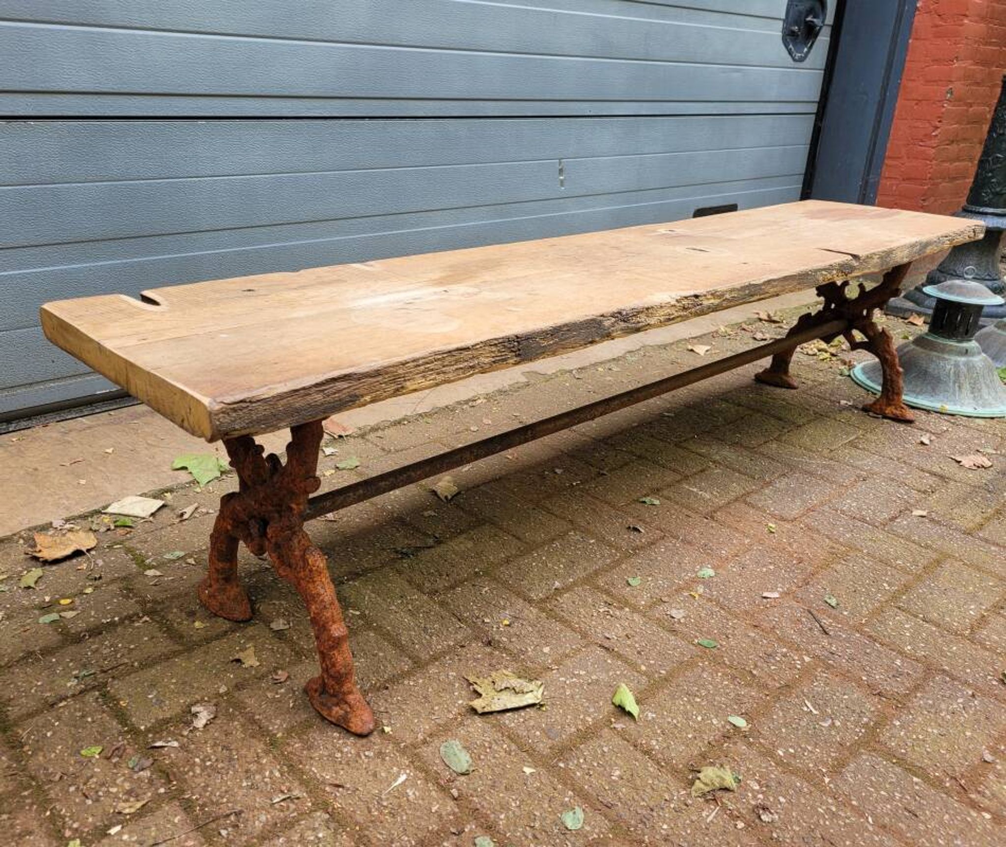 French country-style cast iron garden bench with old barn wood plank.