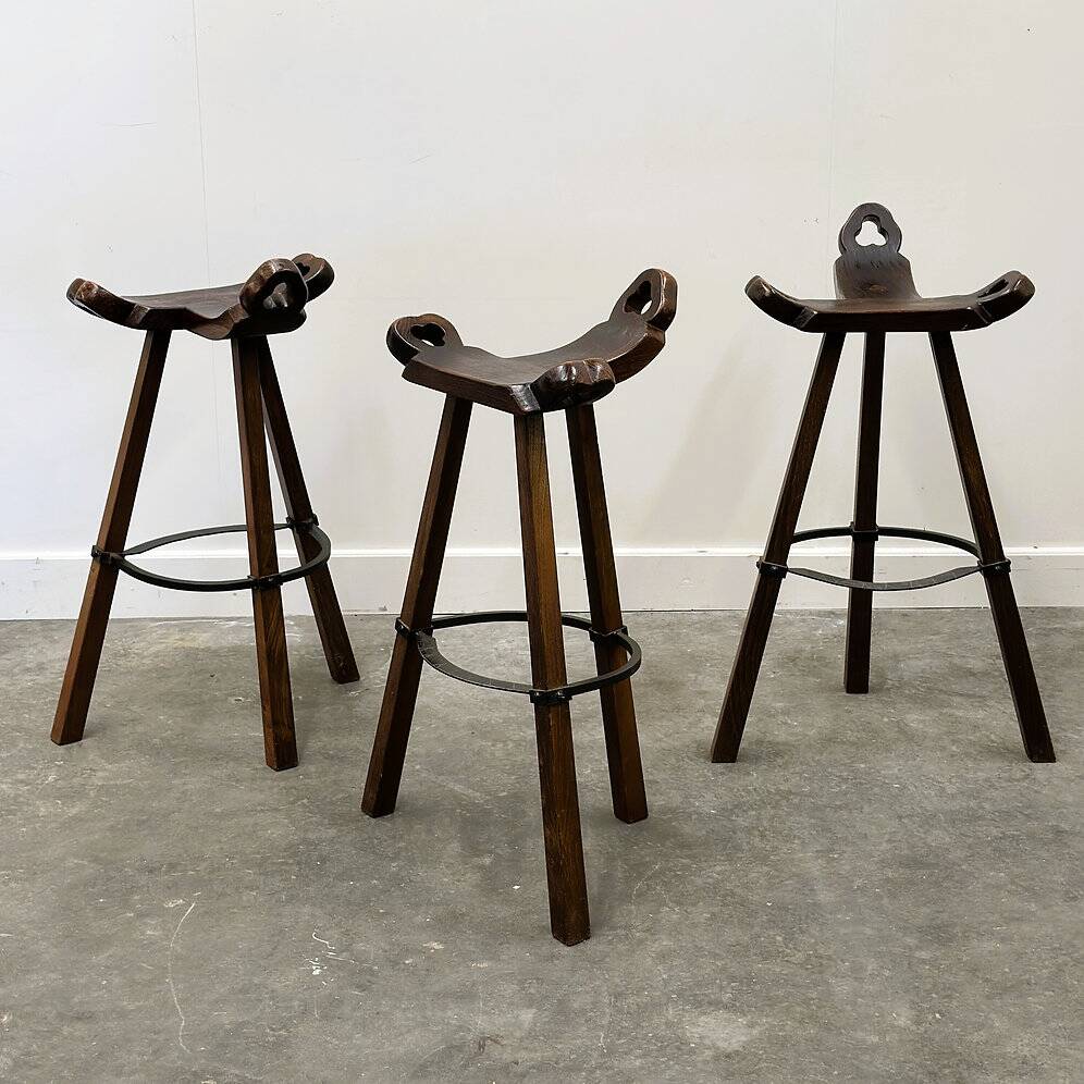 Set of 3 rustic carved oak bar stools with iron footrests, 1970s