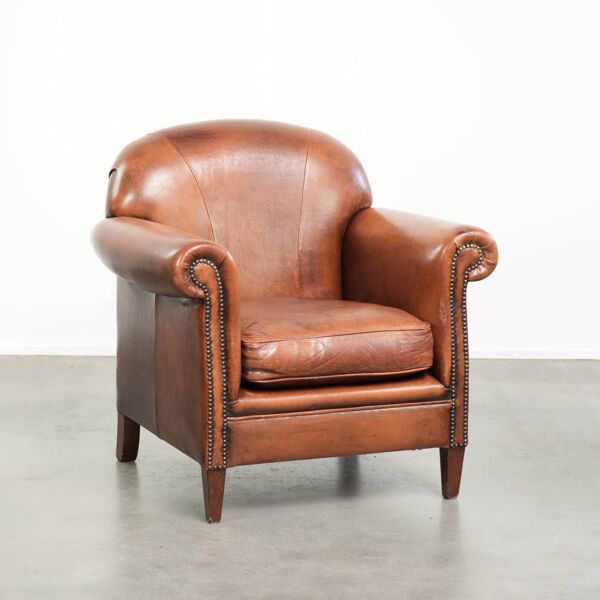 Fauteuil en peau de mouton vintage confortable, fini avec des clous décoratifs.