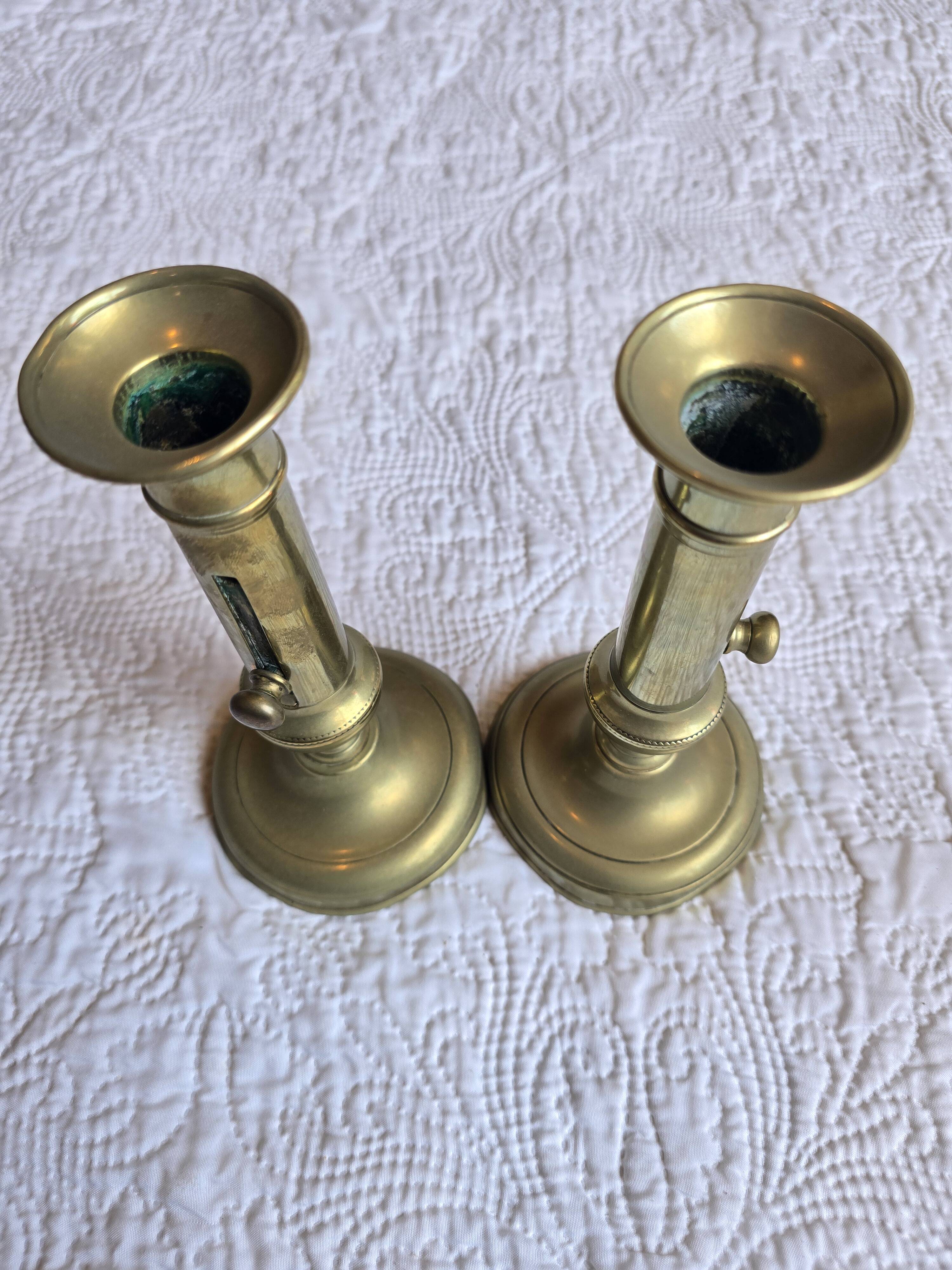 Pair of antique brass candlesticks with adjustable push mechanism from the 19th century.