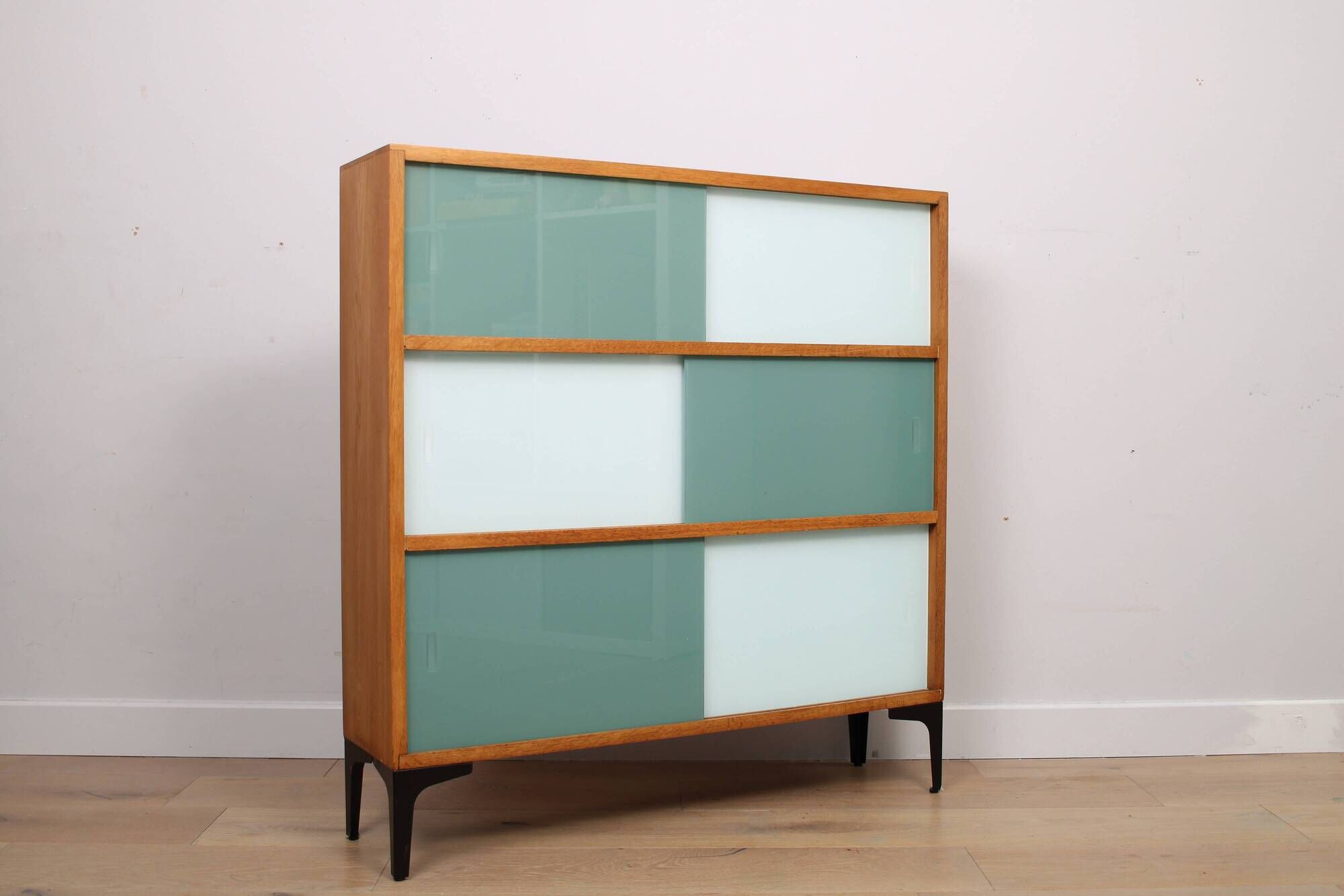 A vintage mid-century 3 tiered bookcase with glass sliding doors
