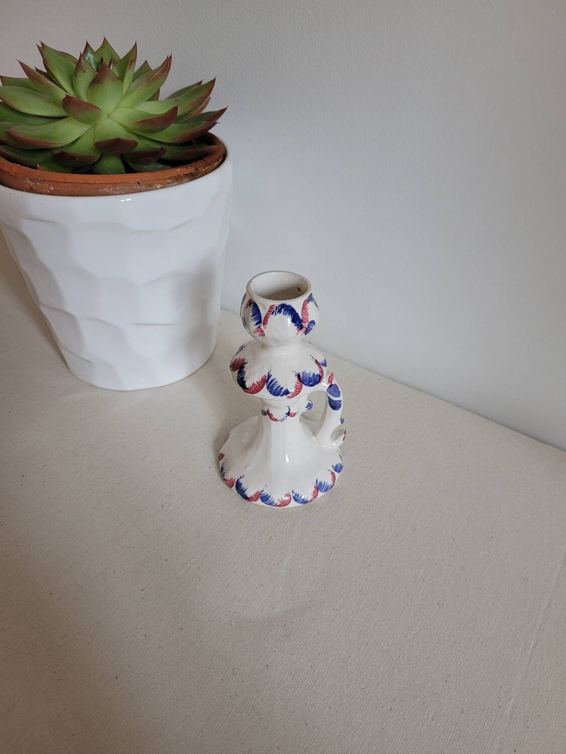 Ceramic candlestick with red and blue decoration.