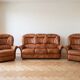 Living room set: 3-seater sofa and 2 brown leather armchairs.