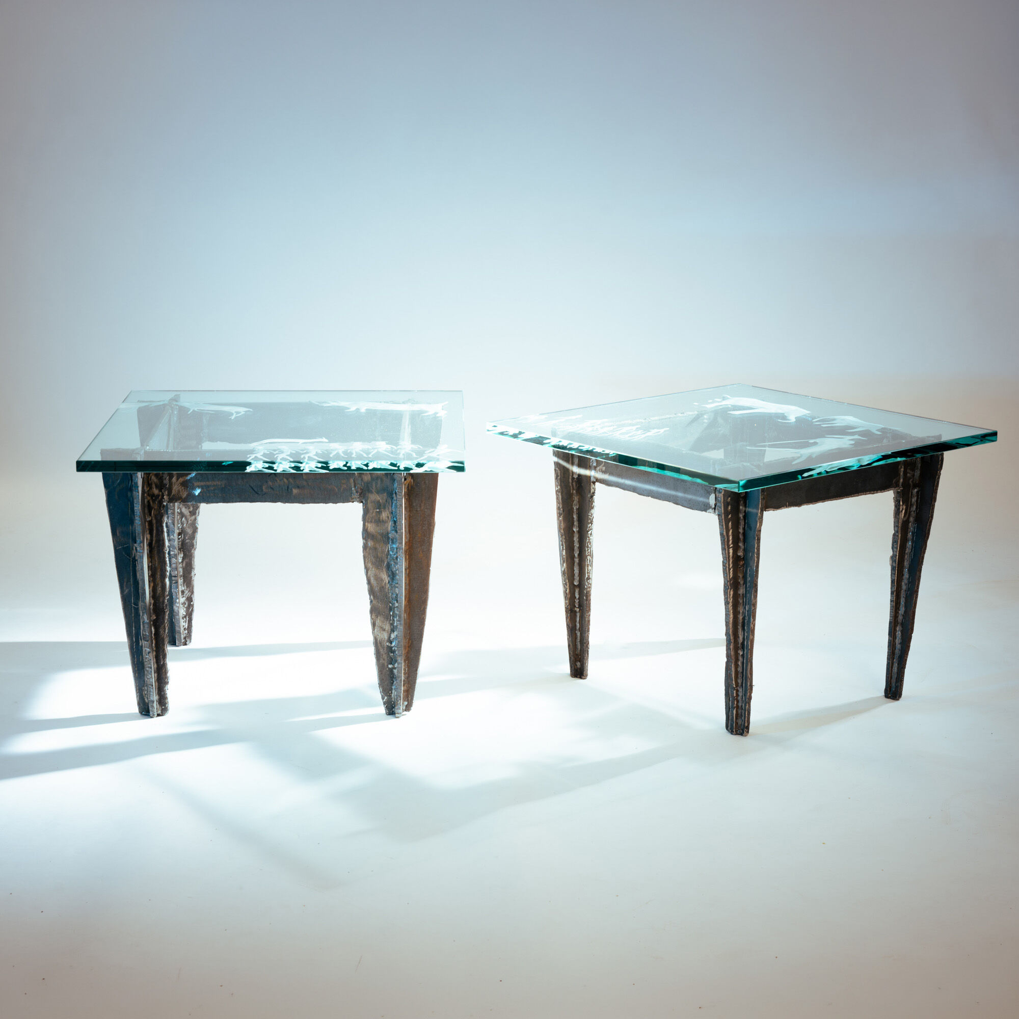 2 brutalist steel side tables with primitive  scene motifs etched glass