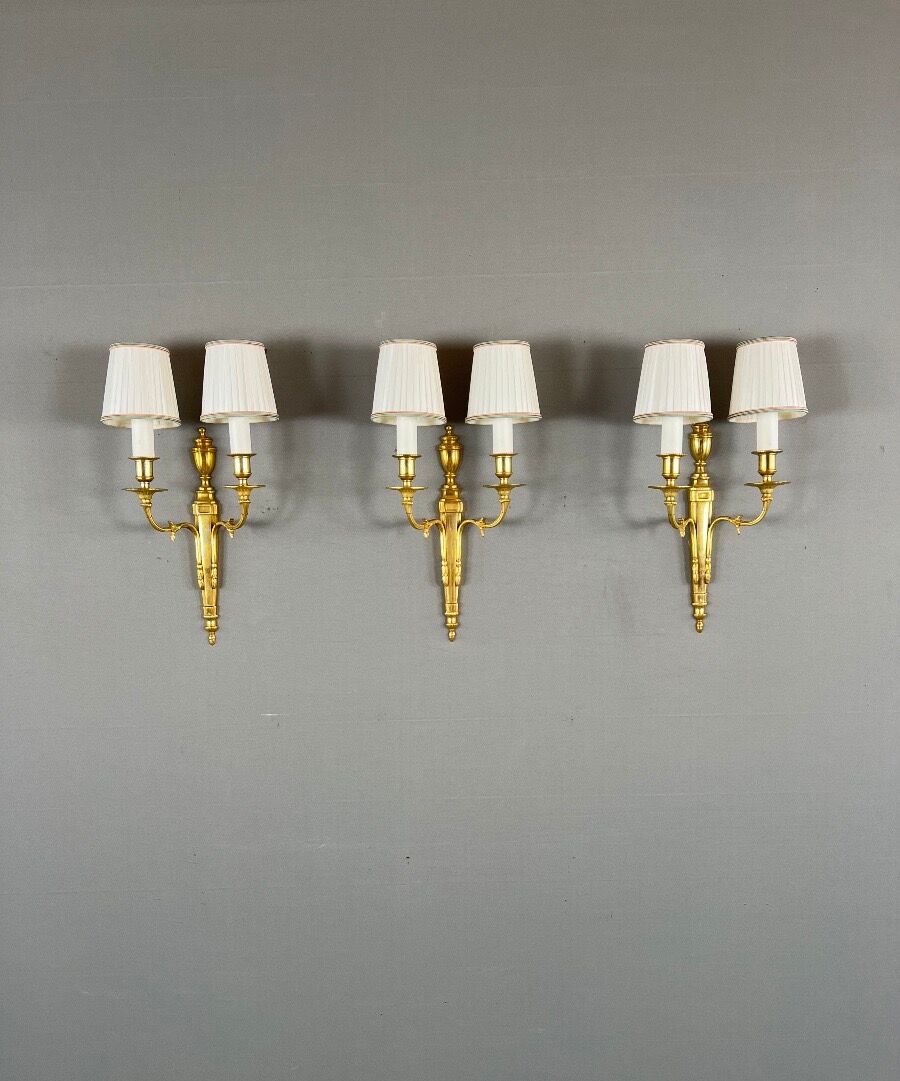 Set of three Louis XVI style wall sconces in gilded bronze, 20th century.
