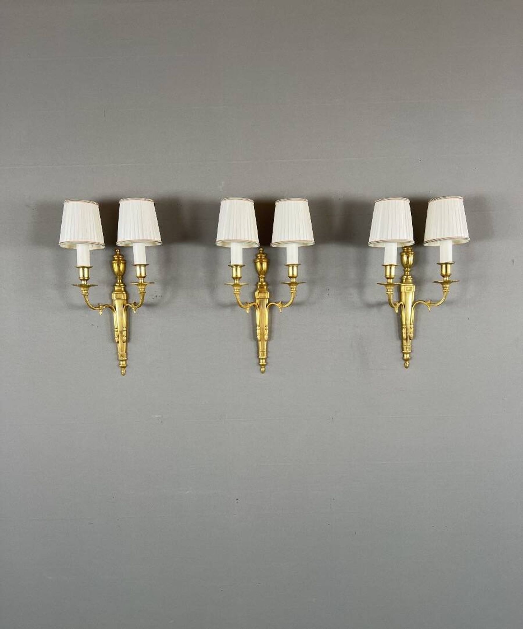 Set of three Louis XVI style wall sconces in gilded bronze, 20th century.