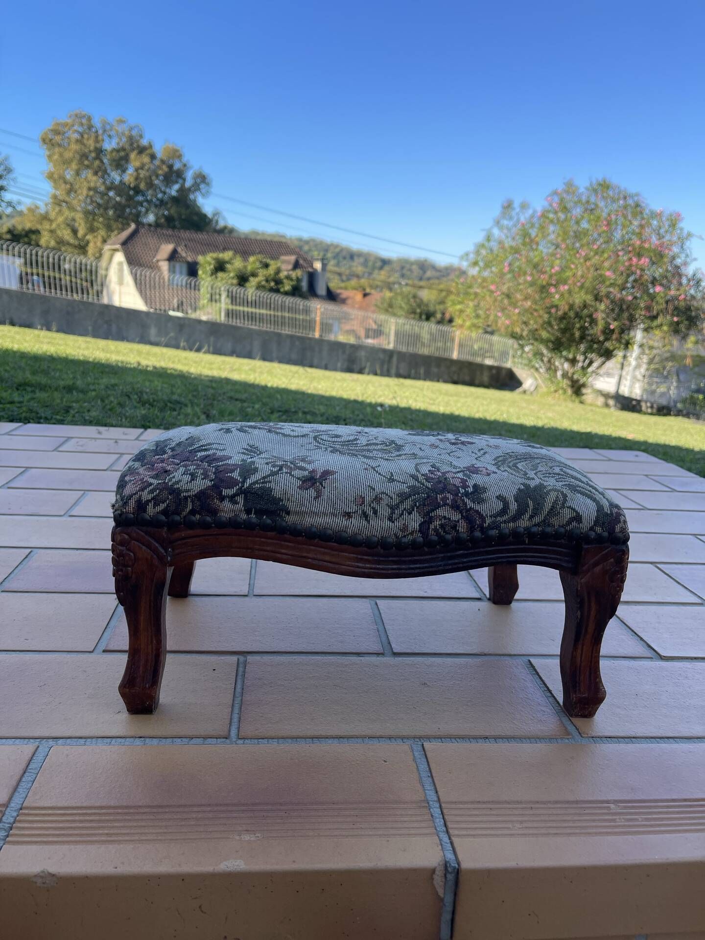 Antique wooden footstool with hand-carved details and floral upholstery –