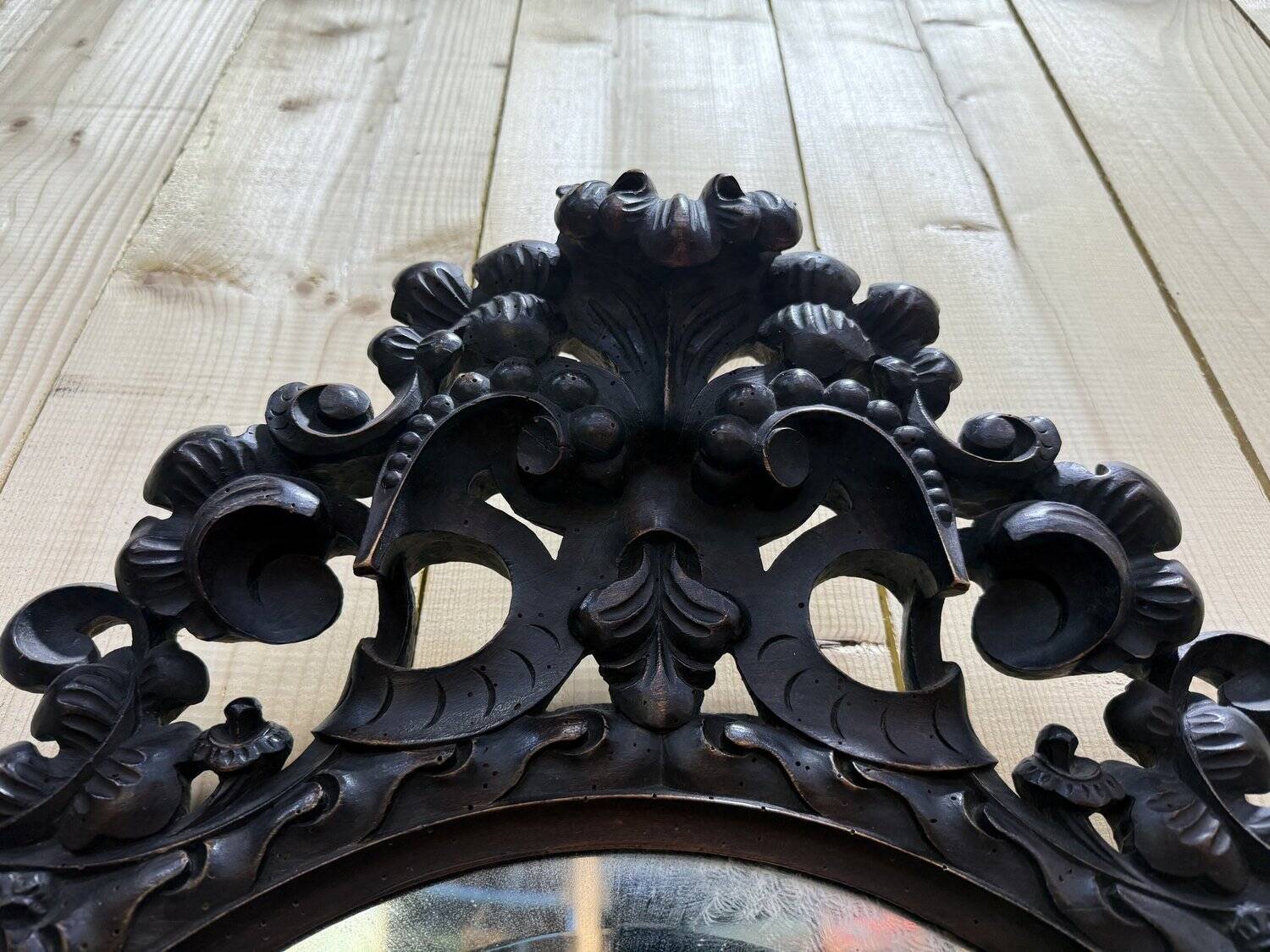 Oval mirror in carved wood with dragon heads.