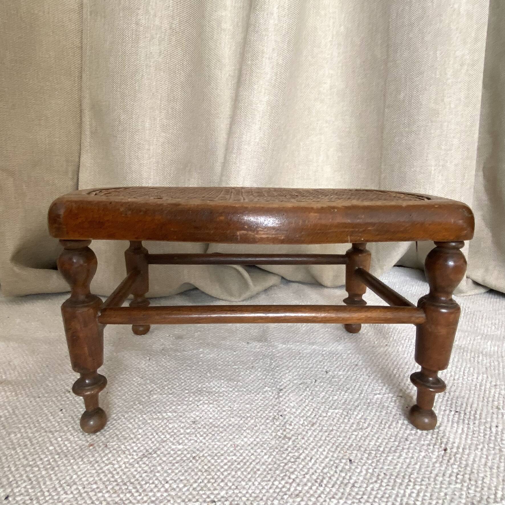 Low wooden stool with caning, footrest.