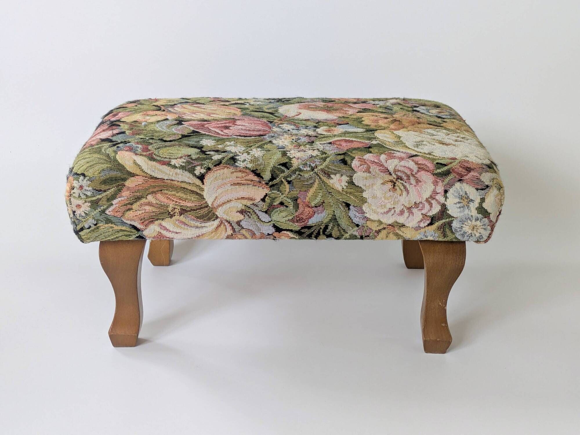 Large vintage upholstered footstool with curved legs.