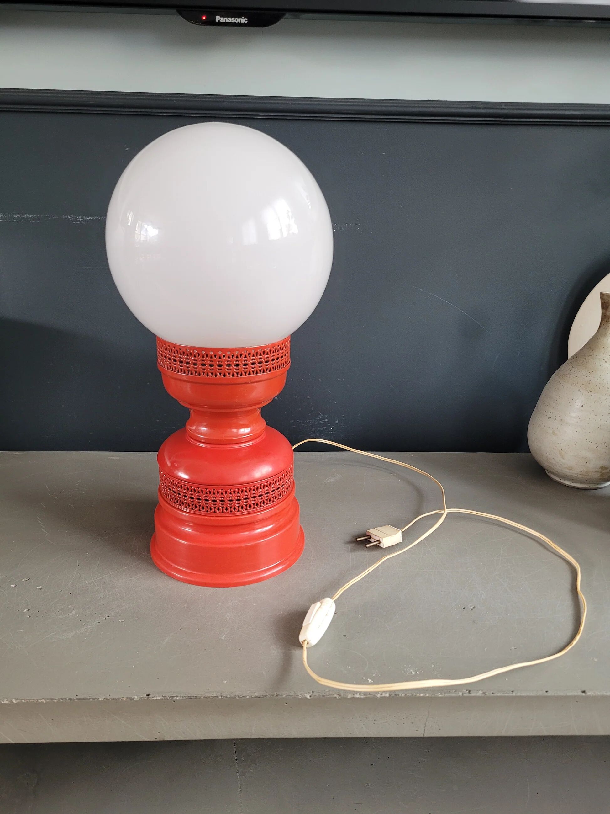 Vintage globe lamp with a metal base, perforated and lacquered in red.