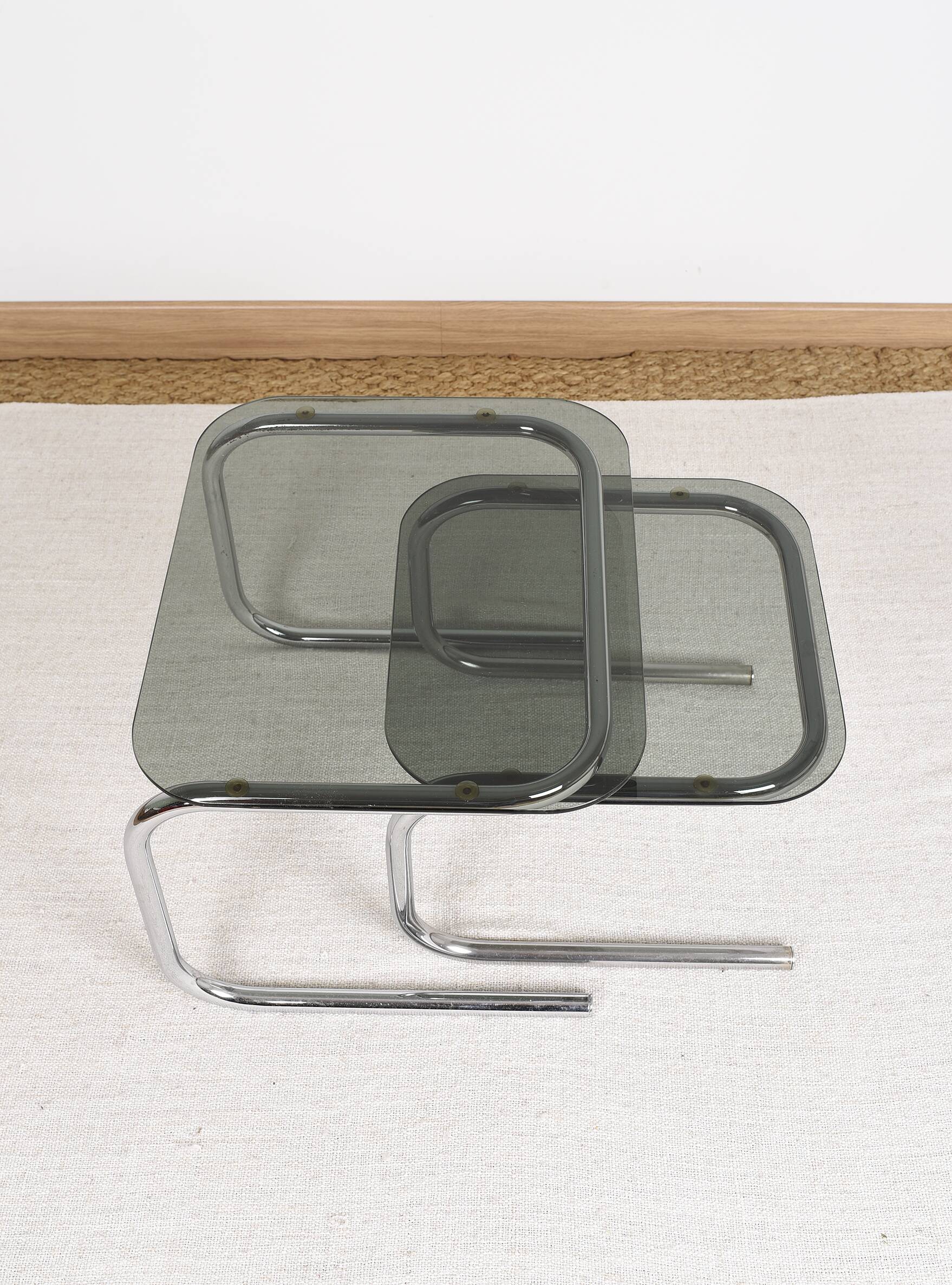 Pair of nesting tables in smoked glass and chrome legs.