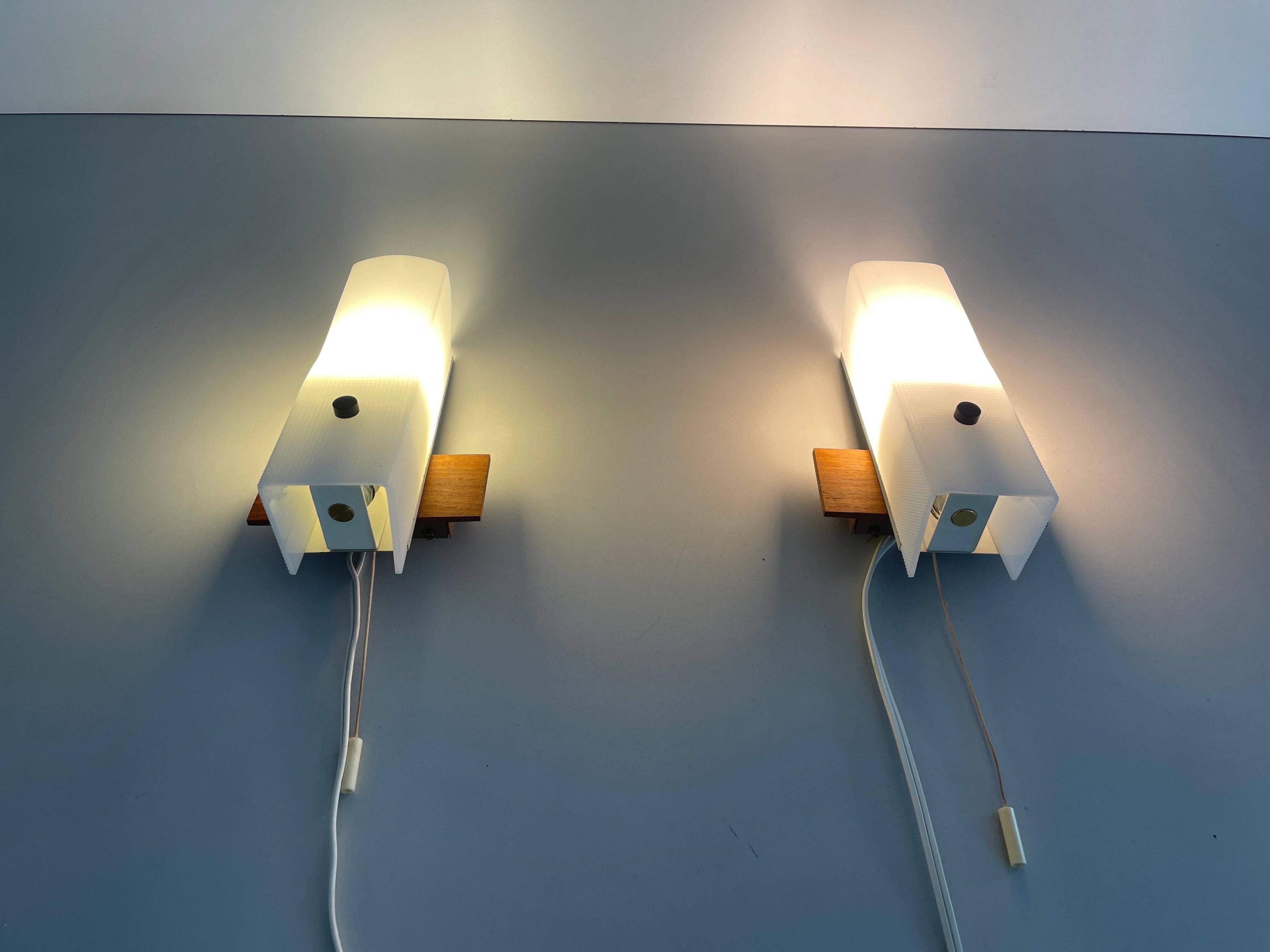 Mid-century wall lights in white plexiglass with a wooden base, 1960s, Germany.