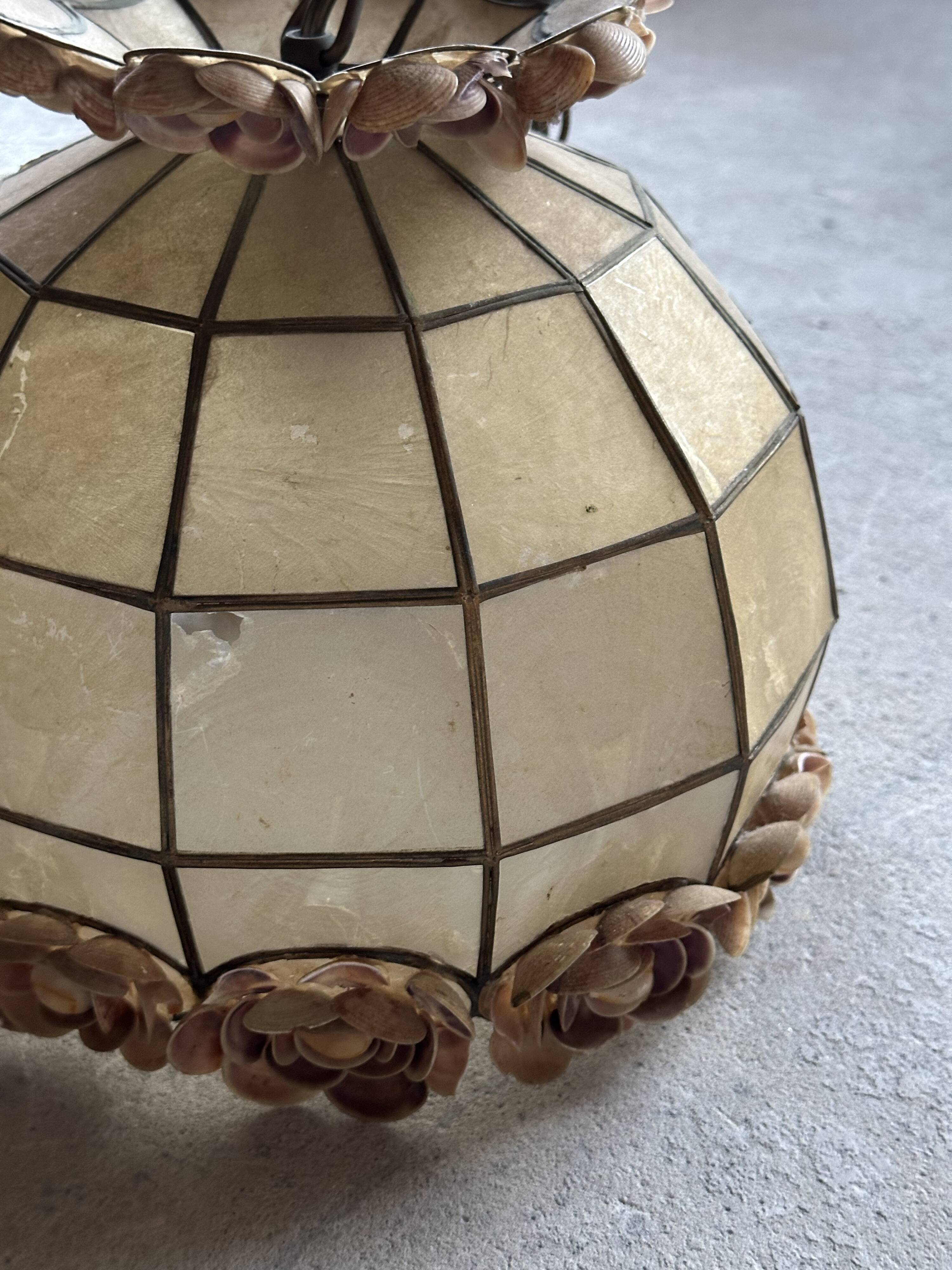 Vintage pendant light with a pearlescent shade and floral decoration.
