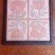 Ceramic tile trivet with floral patterns in pastel tones.