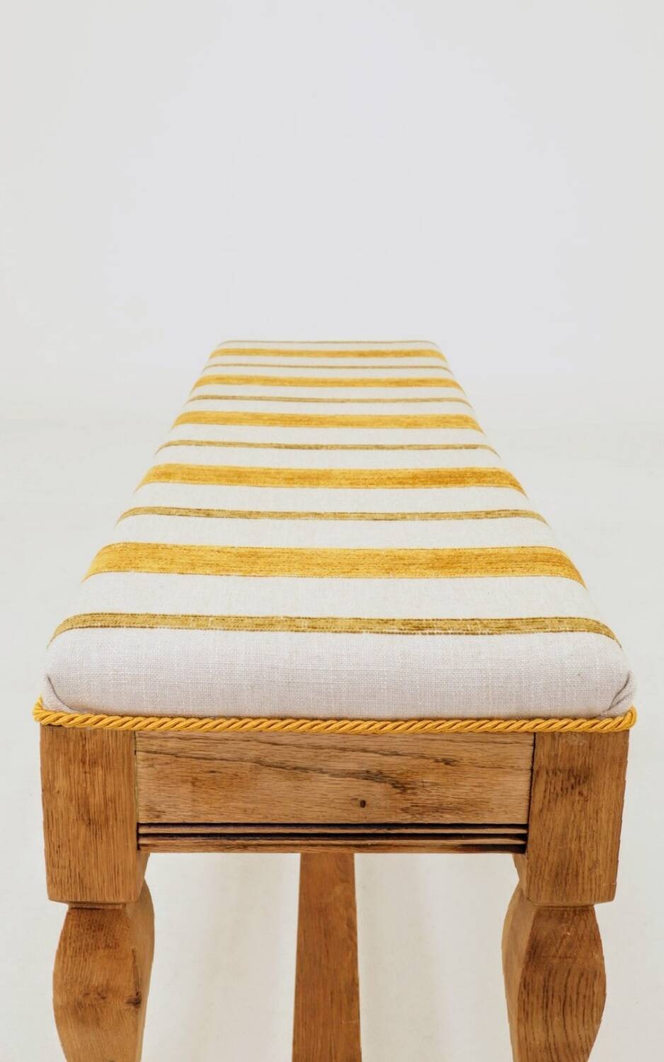 Vintage oak bench with striped linen fabric in a country style.