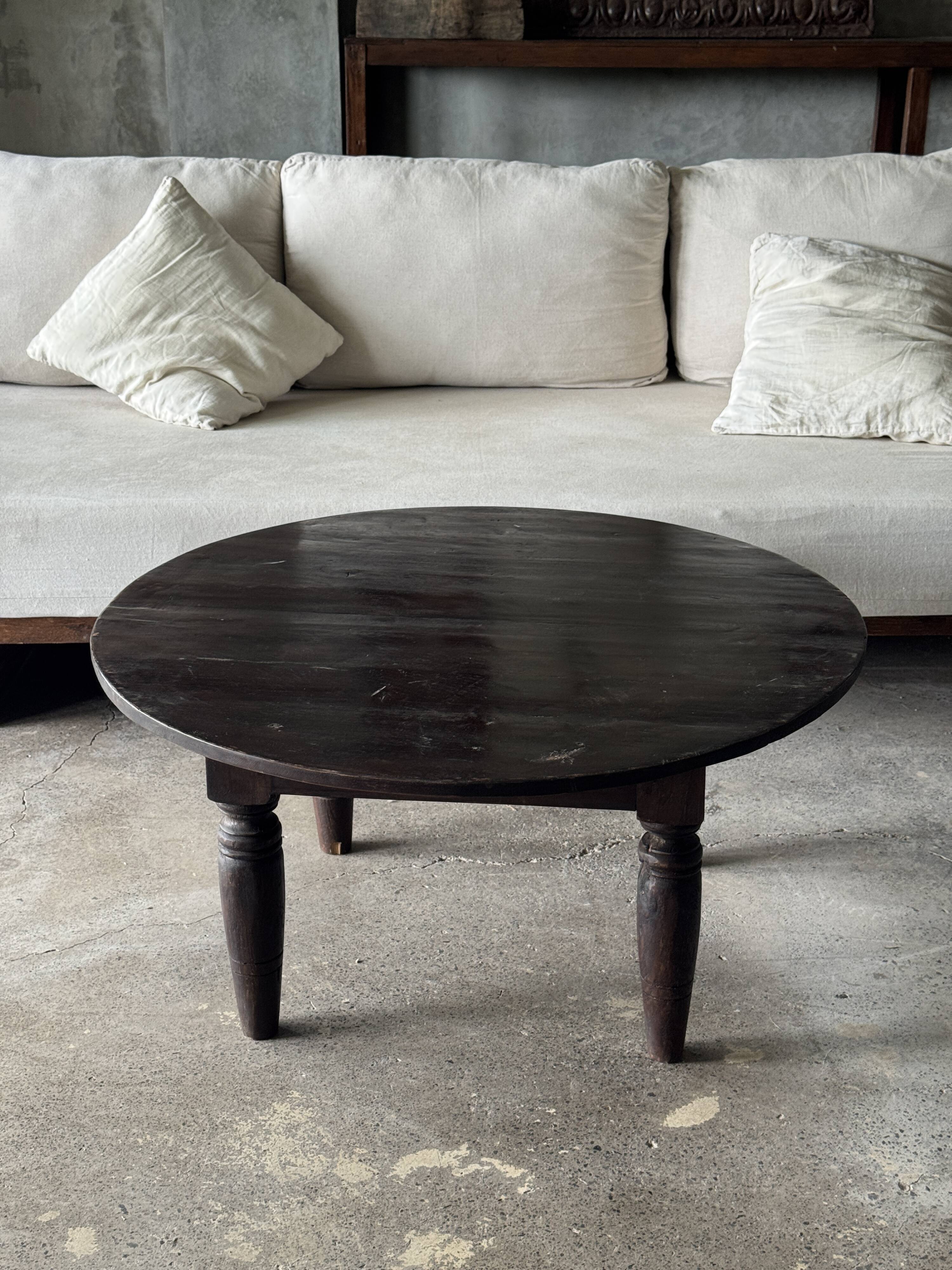 Antique round coffee table in Indonesian teak with turned legs.