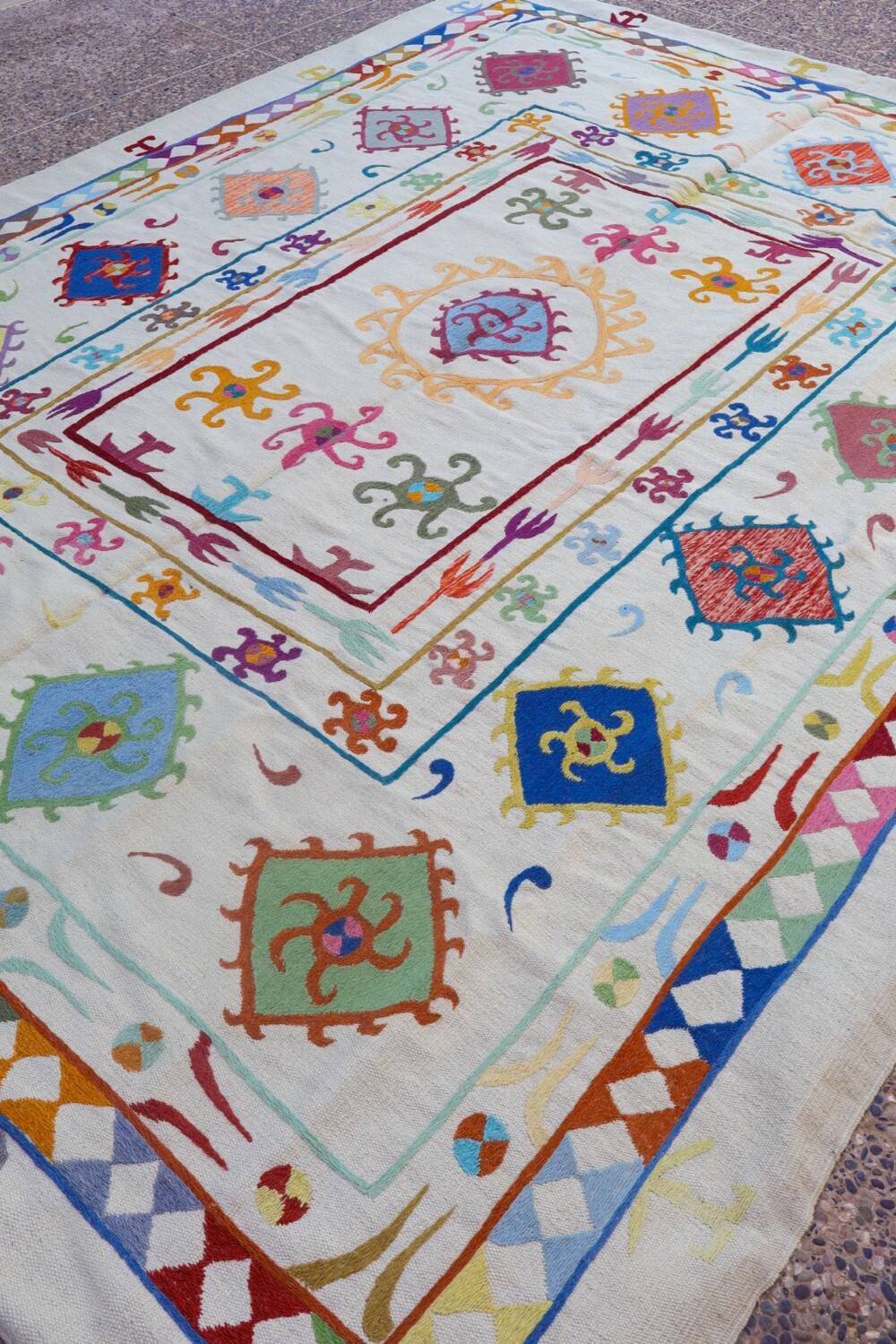 White suzani kilim rug with multi-colored embroidered patterns