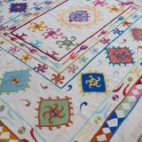 White suzani kilim rug with multi-colored embroidered patterns