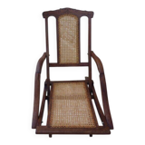 Antique folding chair with caned seat and backrest made of wood.