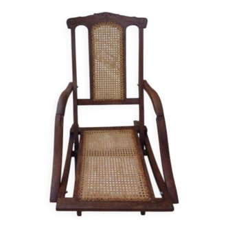Antique folding chair with caned seat and backrest made of wood.