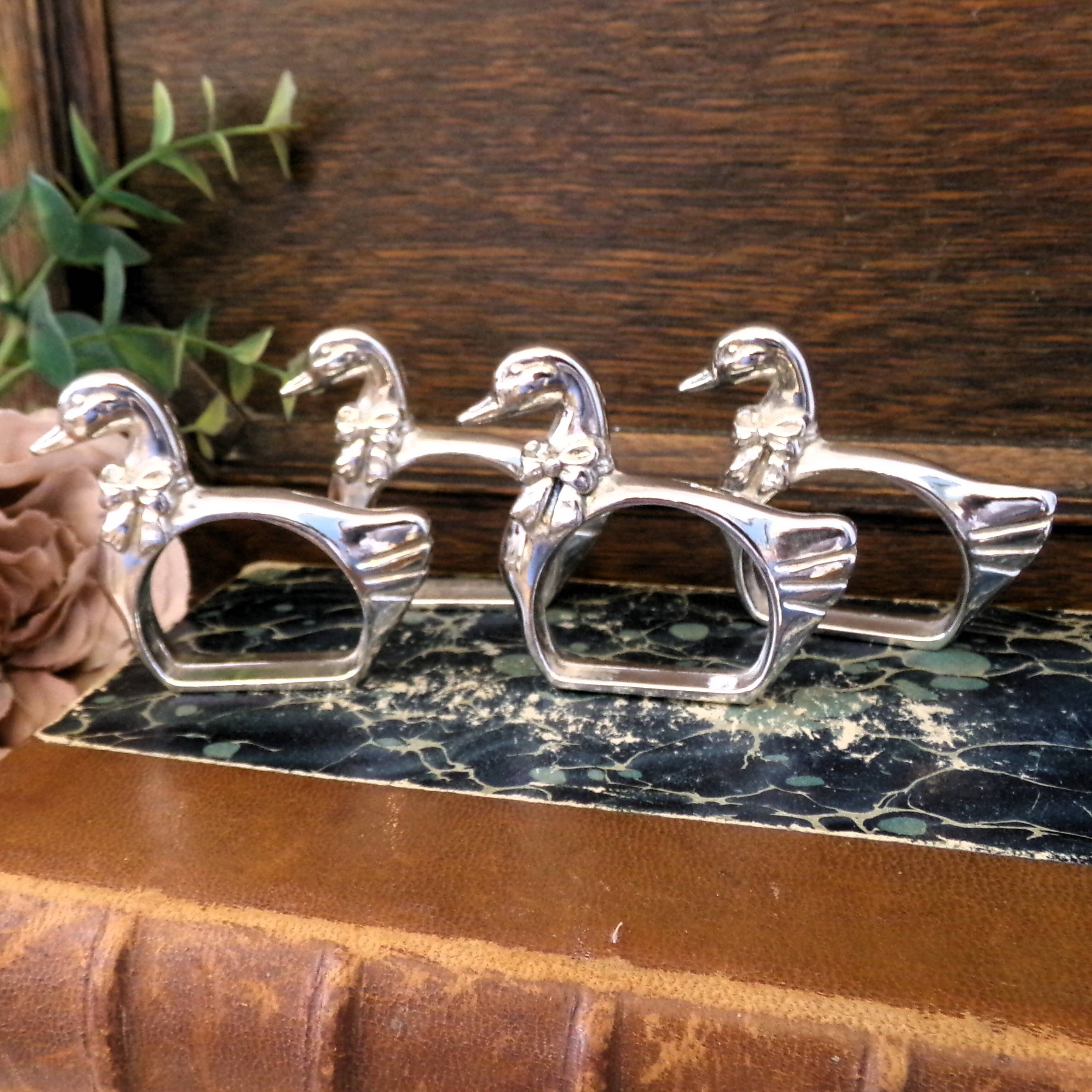 Four silver-plated napkin rings in the shape of a duck/goose