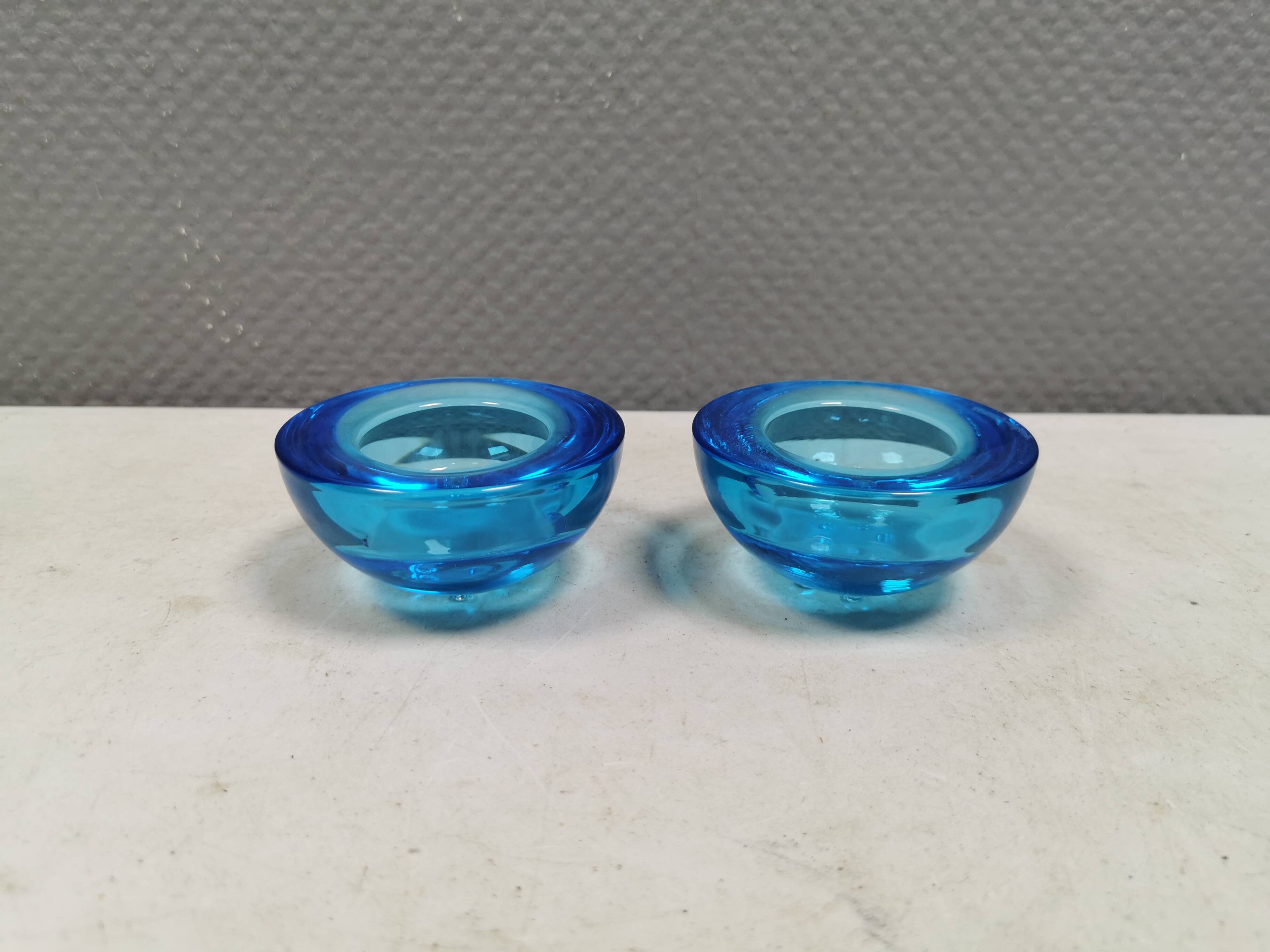 A set of iitalla candle holders in blue transparent glass.
