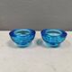 A set of iitalla candle holders in blue transparent glass.