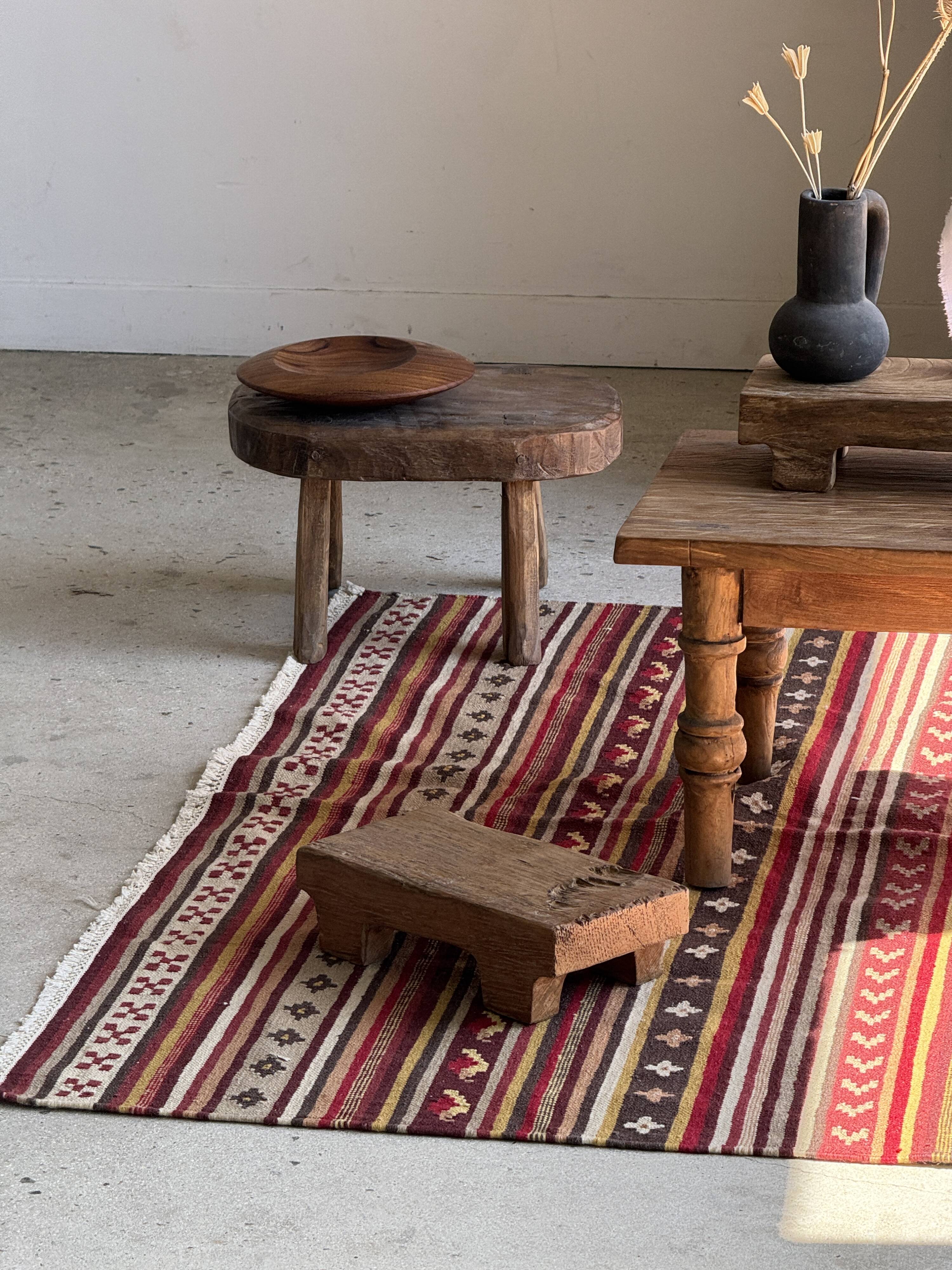 Large Indian rug with red, yellow, and white stripes and geometric fringes.