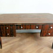A large Art Deco style rosewood desk with 5 drawers and decorative motifs