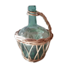 Vintage green demijohn surrounded by natural wicker