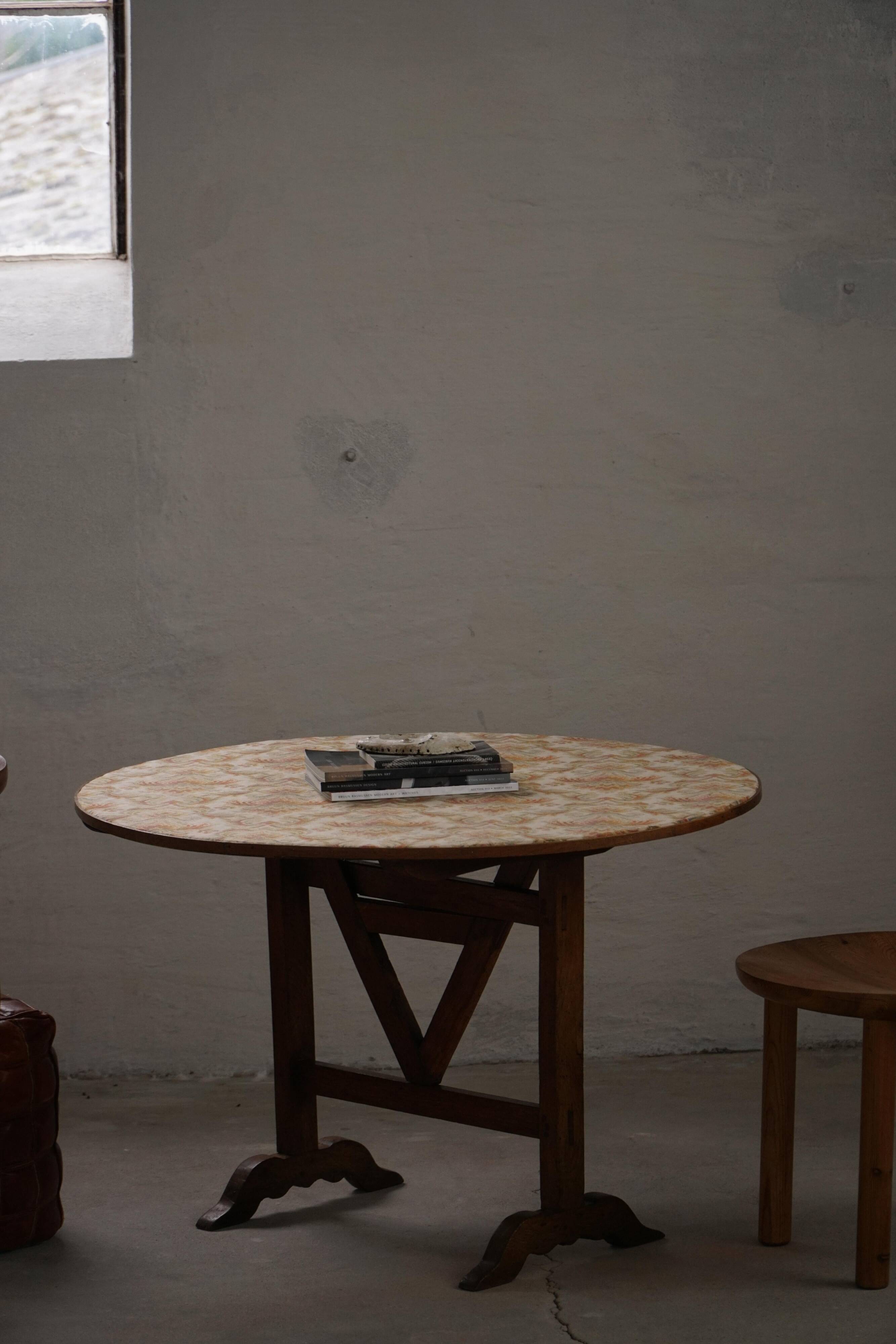 19th-century French round wine table with an adjustable top and floral textile surface.