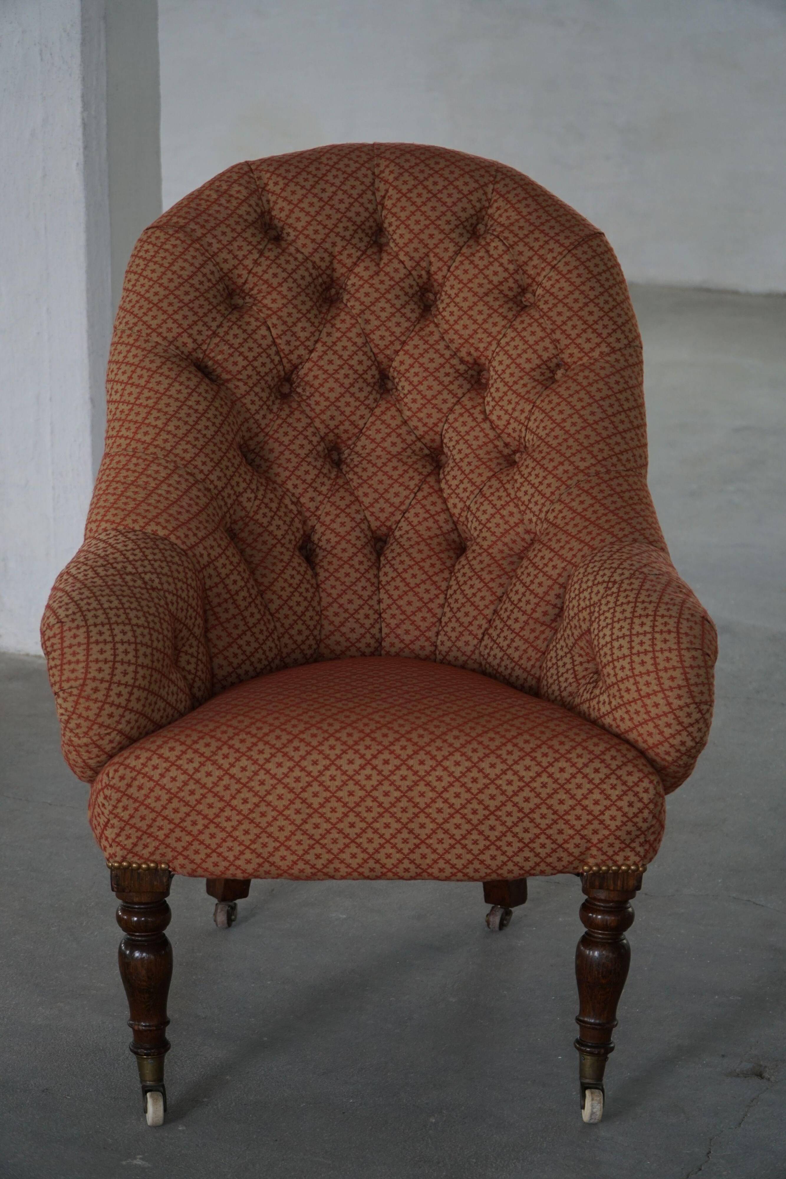 Victorian mahogany armchair, with wheels and coloured fabric, England, early 1900s.