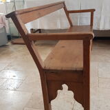 Church bench in fir tree with armrests