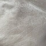 Damask tablecloth with a floral pattern and a central embroidered monogram.