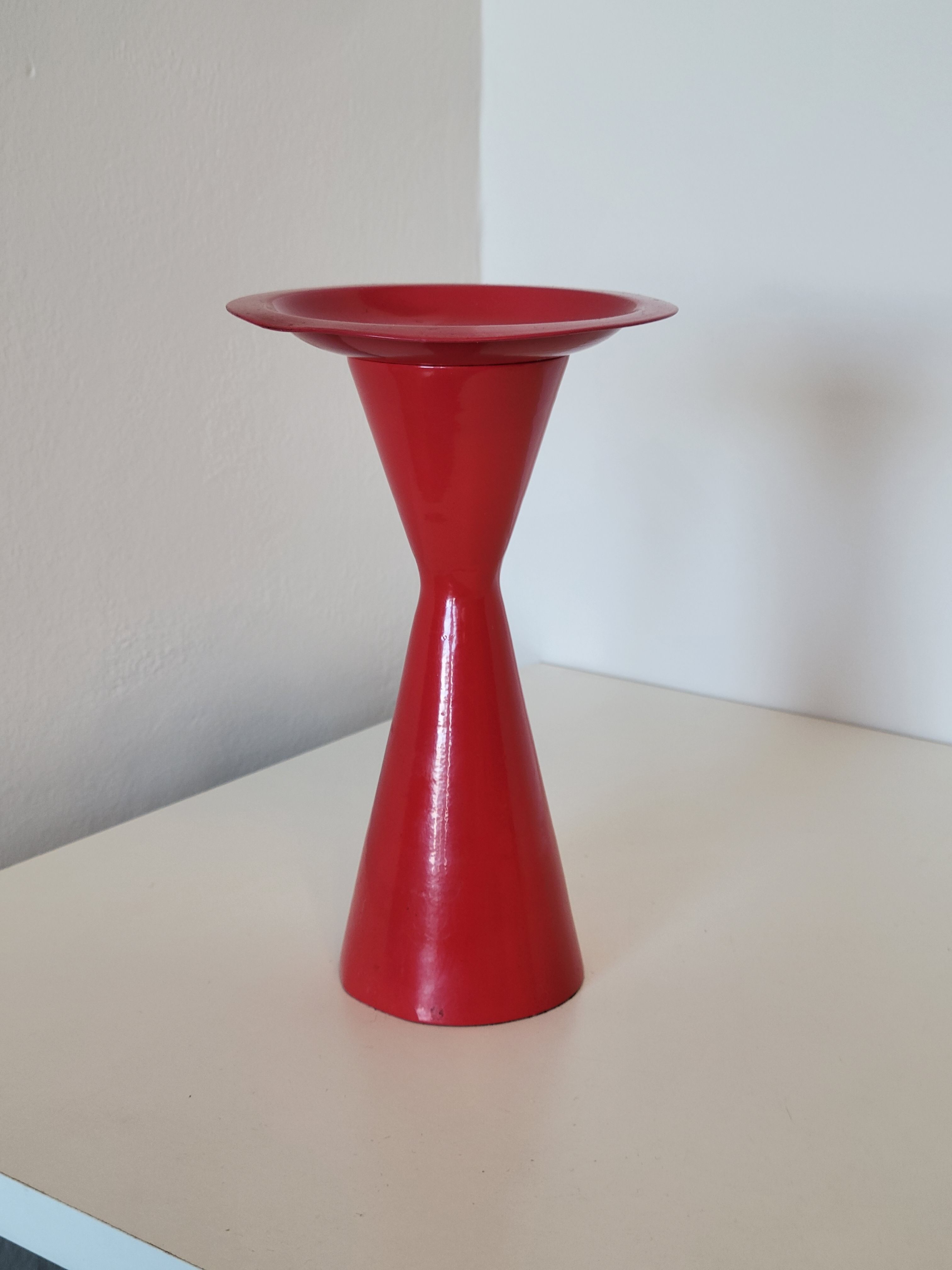Vintage design candlestick in red metal in the shape of an hourglass