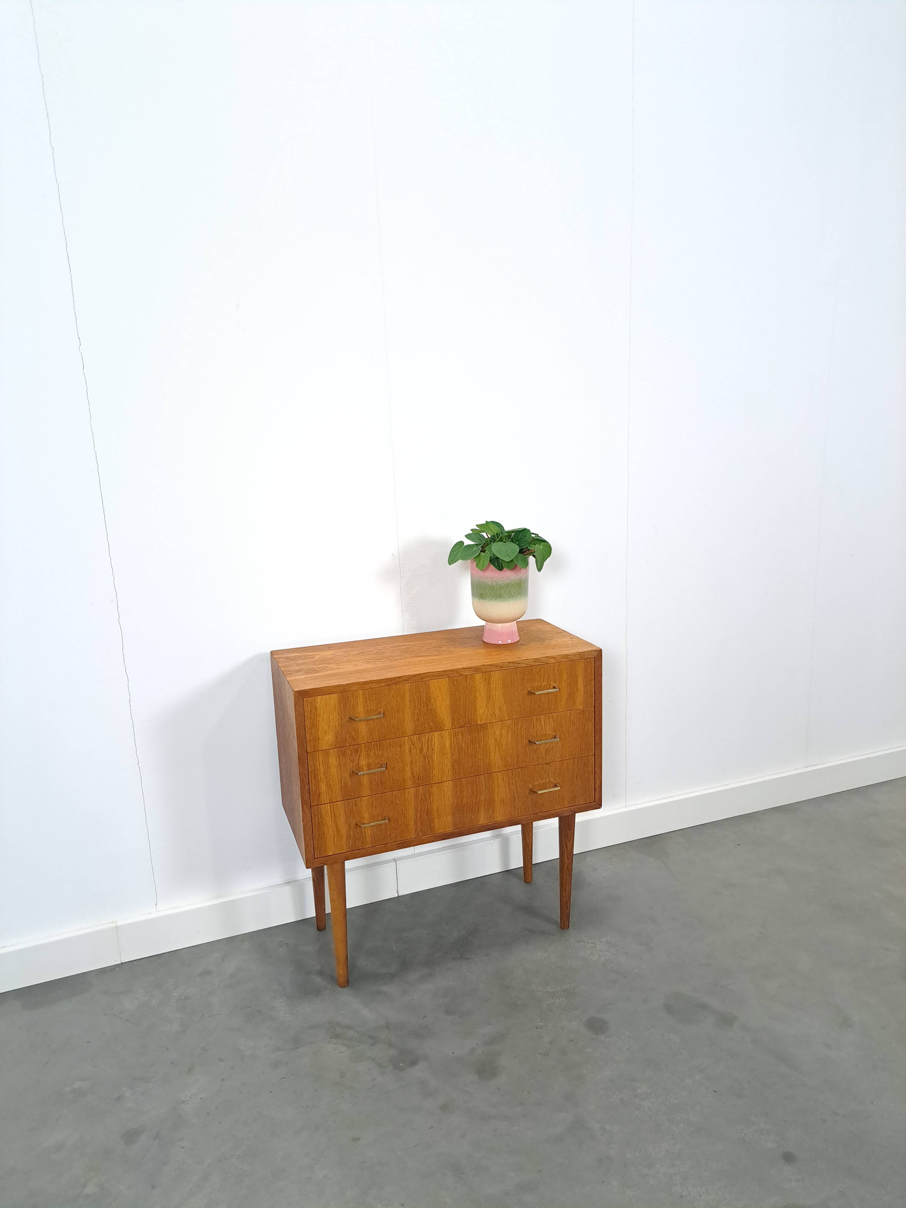 Commode danoise avec de hauts pieds et des poignées dorées.