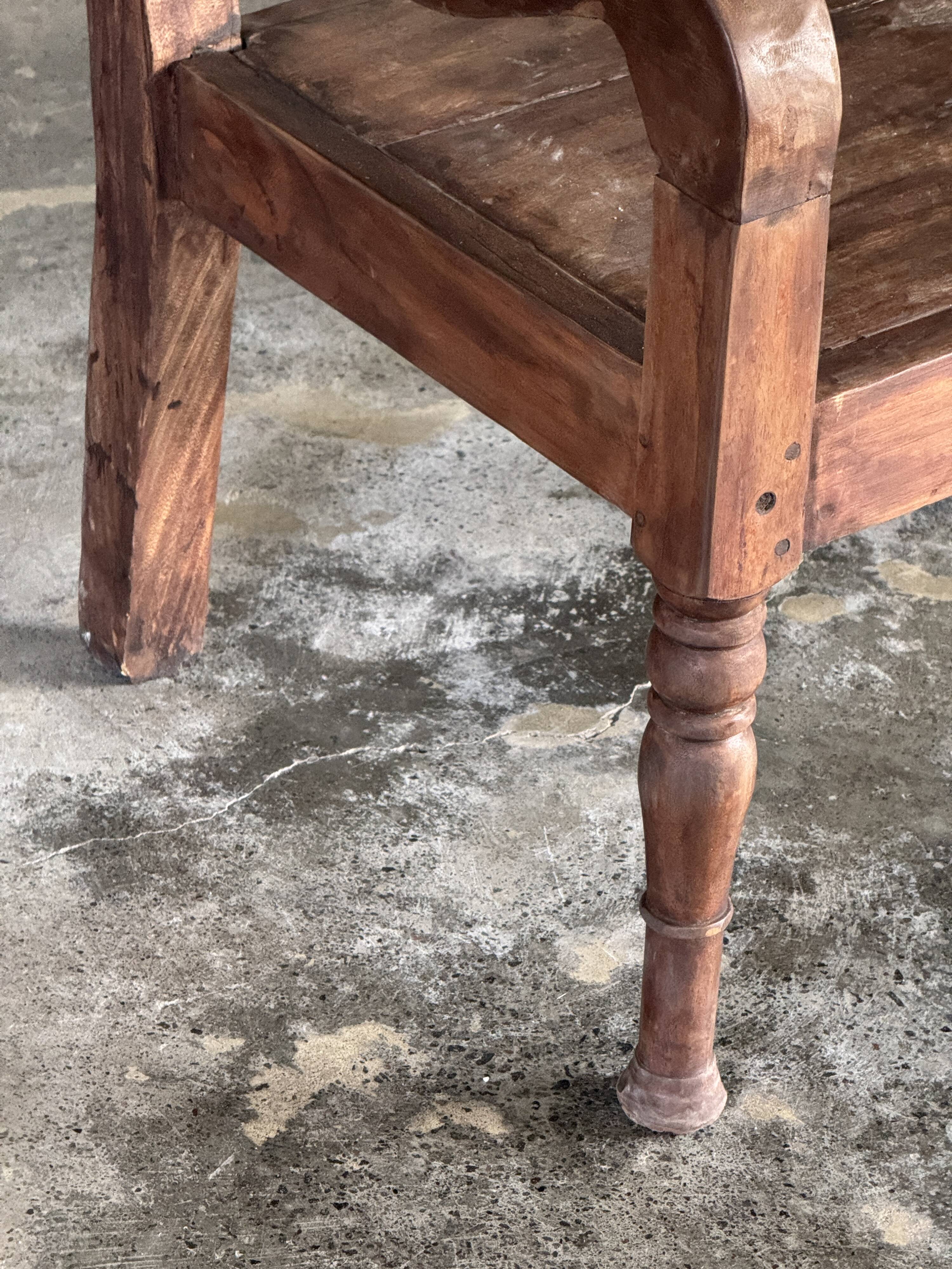 Small antique Indonesian bench in carved teak with plant and floral motifs.