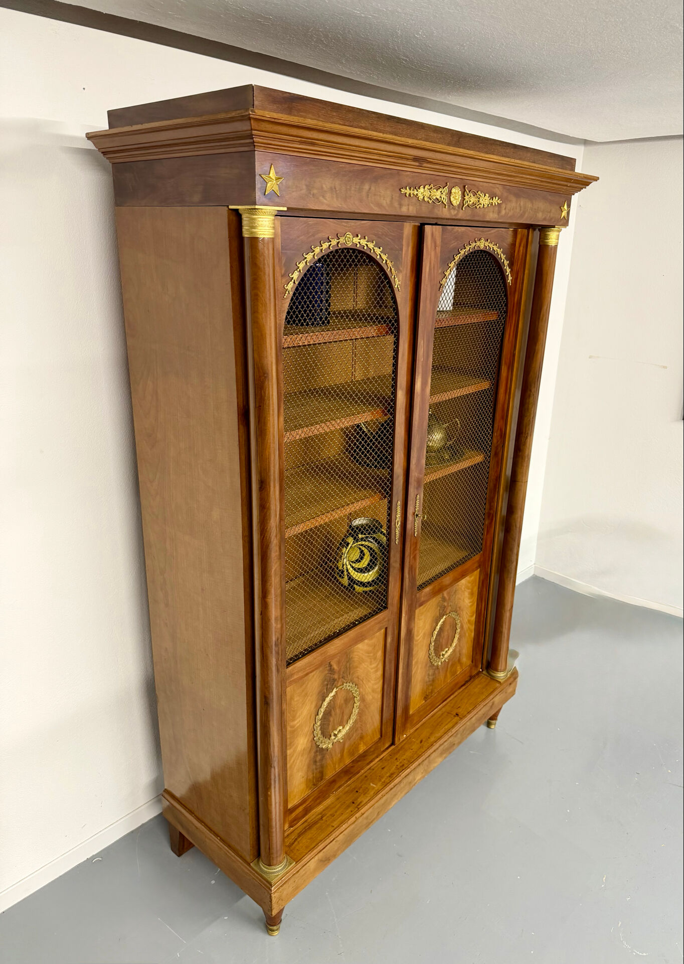 Large Empire-style library in wood with gilded bronze ornaments.