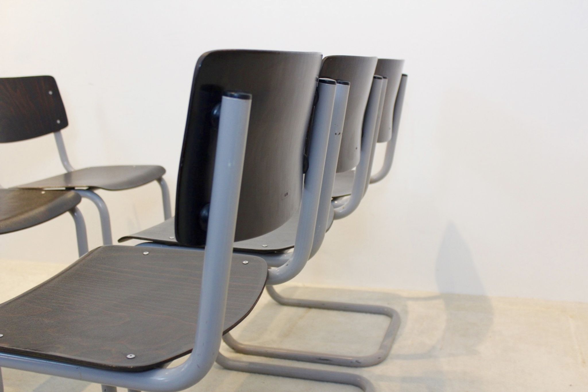 Ensemble de six chaises industrielles en contreplaqué Gispen dans un cadre gris et wengé.